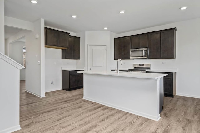 kitchen featuring sink, stainless steel appliances, light hardwood / wood-style flooring, an island with sink, and dark brown cabinets