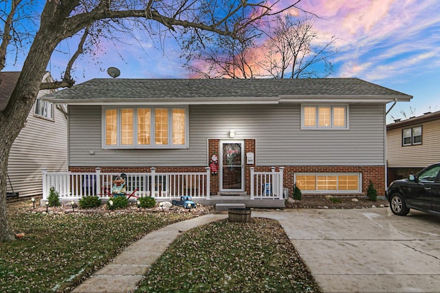 raised ranch featuring a porch and a lawn