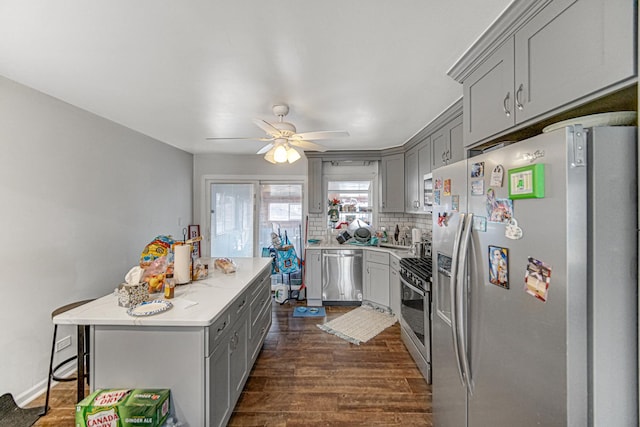 kitchen with dark hardwood / wood-style floors, gray cabinetry, decorative backsplash, a center island, and stainless steel appliances