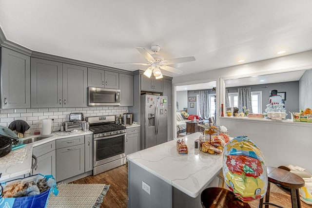 kitchen featuring dark hardwood / wood-style flooring, decorative backsplash, gray cabinets, and appliances with stainless steel finishes