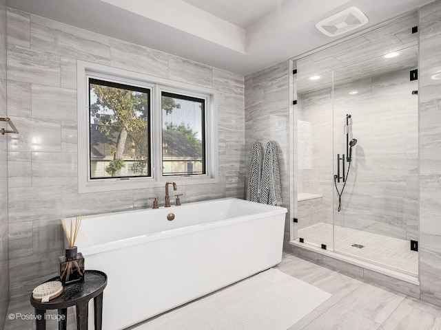 bathroom with separate shower and tub and tile walls