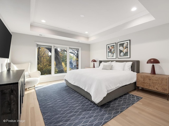 bedroom with hardwood / wood-style flooring, a raised ceiling, and ornamental molding