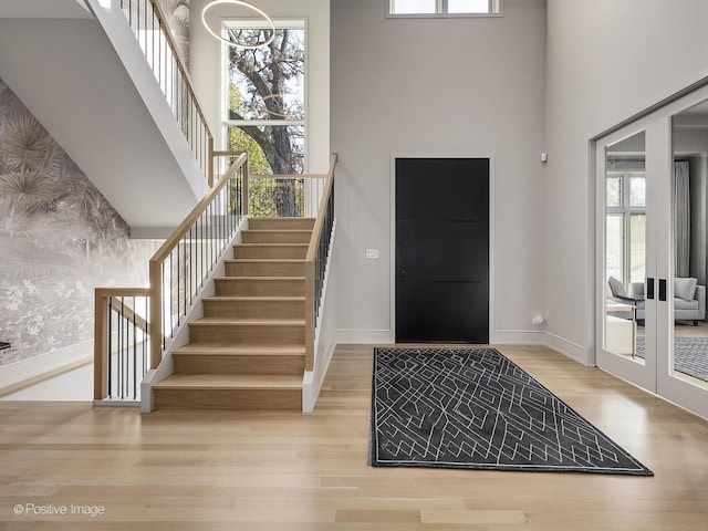 foyer featuring french doors, light hardwood / wood-style flooring, and a high ceiling