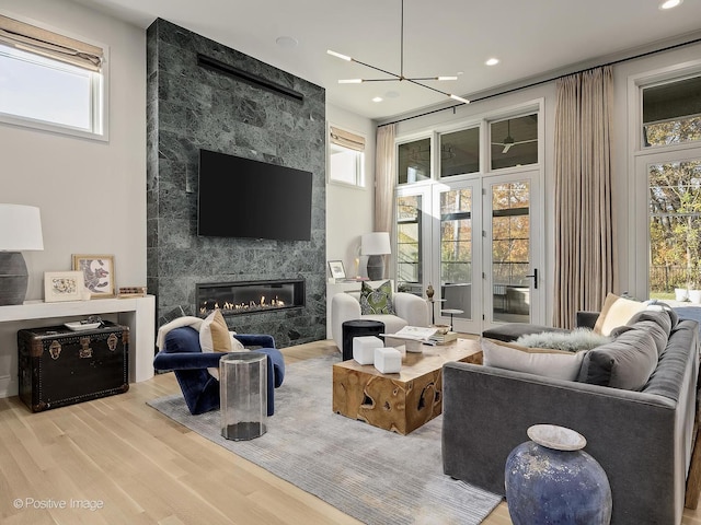 living room with a notable chandelier, a fireplace, and light hardwood / wood-style flooring