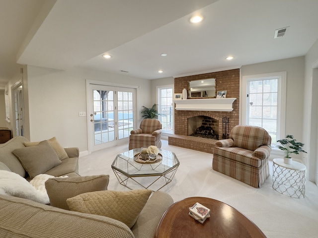 carpeted living room with french doors, a brick fireplace, and a wealth of natural light