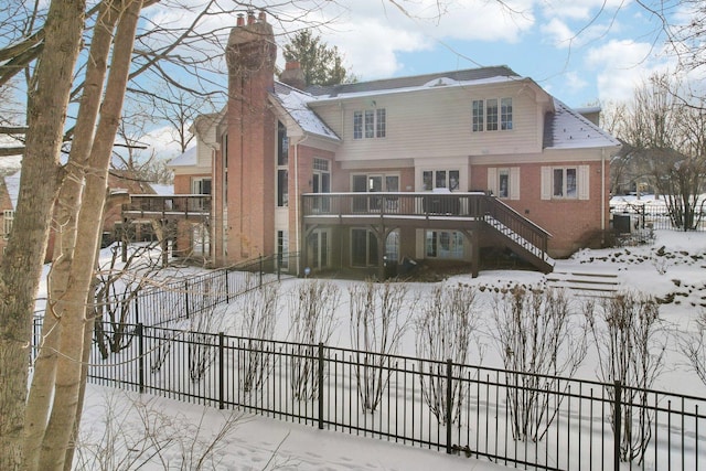 snow covered house featuring a wooden deck