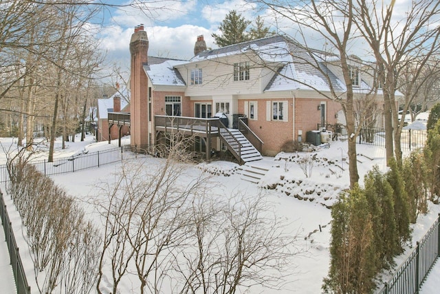 snow covered back of property featuring a wooden deck