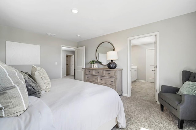 bedroom featuring ensuite bathroom and light carpet