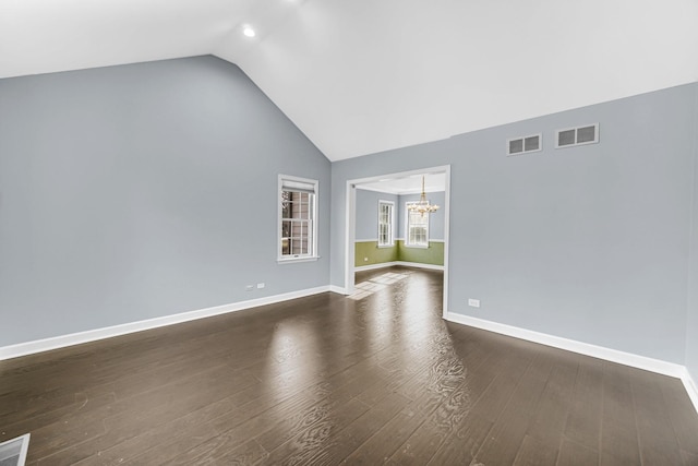 unfurnished room featuring an inviting chandelier, dark hardwood / wood-style flooring, and lofted ceiling