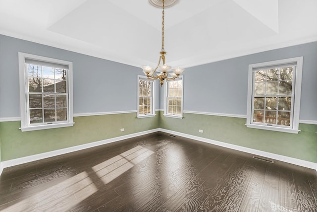 spare room with wood-type flooring, a raised ceiling, and an inviting chandelier