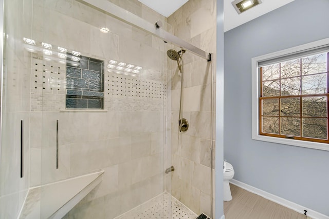 bathroom featuring toilet and a shower with shower door