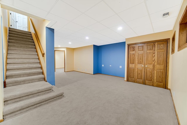 basement with a paneled ceiling and carpet flooring