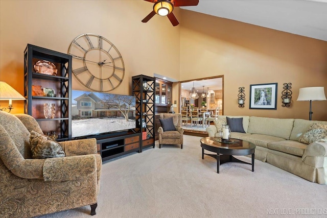 carpeted living room with high vaulted ceiling and ceiling fan with notable chandelier