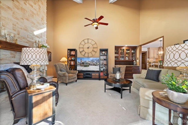 carpeted living room featuring beam ceiling, ceiling fan, and a high ceiling