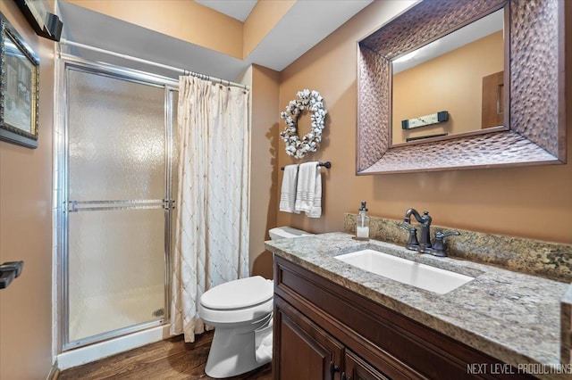 bathroom featuring hardwood / wood-style flooring, vanity, a shower with shower door, and toilet