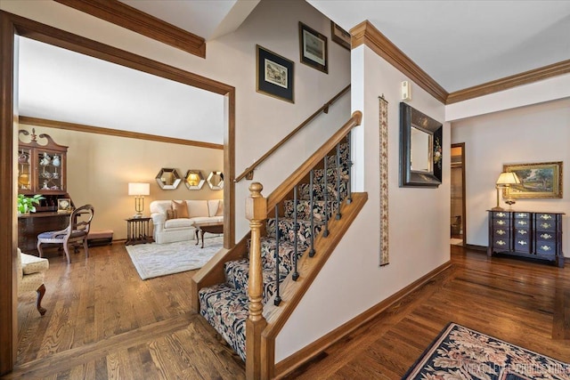 staircase with wood-type flooring and ornamental molding