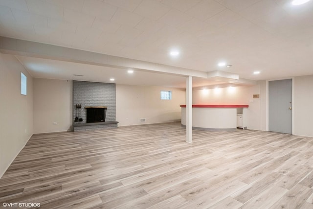 basement with a fireplace, light hardwood / wood-style floors, and plenty of natural light