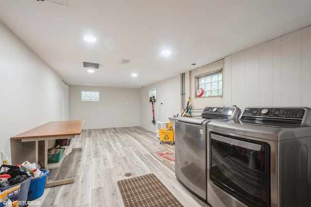 laundry area with washing machine and dryer and light wood-type flooring