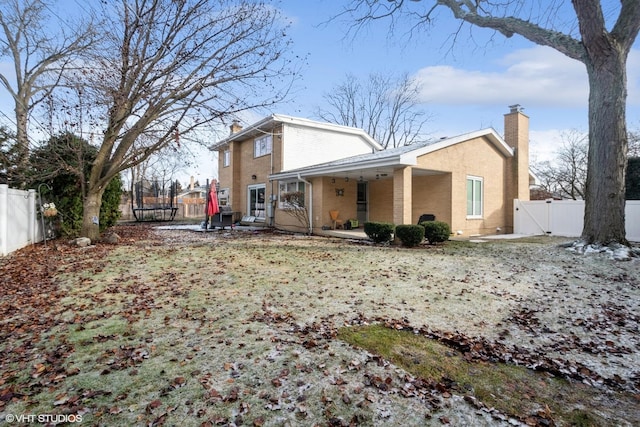 back of house with a trampoline and a patio