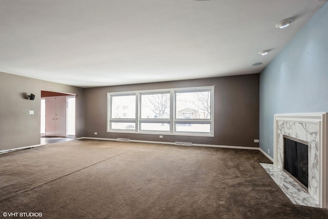 unfurnished living room featuring dark carpet and a high end fireplace