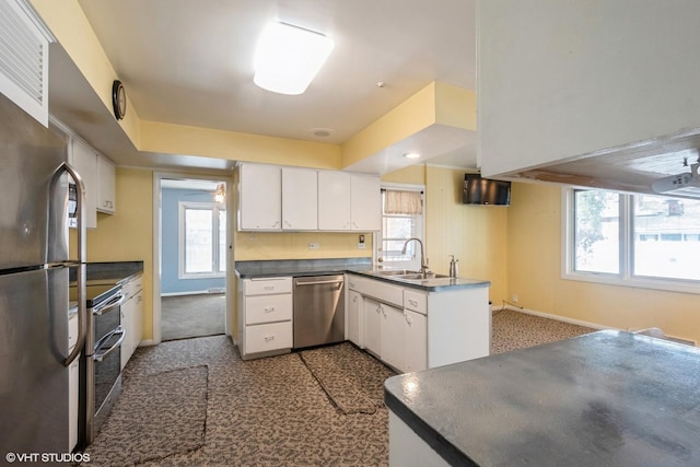 kitchen with carpet, sink, kitchen peninsula, appliances with stainless steel finishes, and white cabinetry