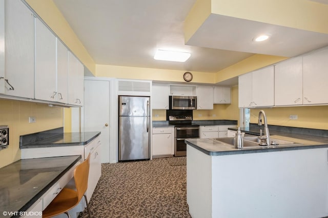 kitchen featuring kitchen peninsula, appliances with stainless steel finishes, white cabinetry, and sink