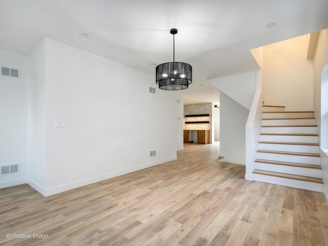 unfurnished living room featuring light hardwood / wood-style flooring and an inviting chandelier