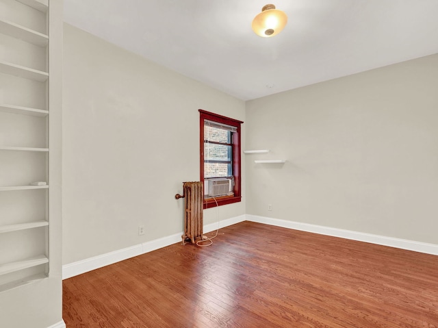 empty room featuring built in features, wood-type flooring, and cooling unit