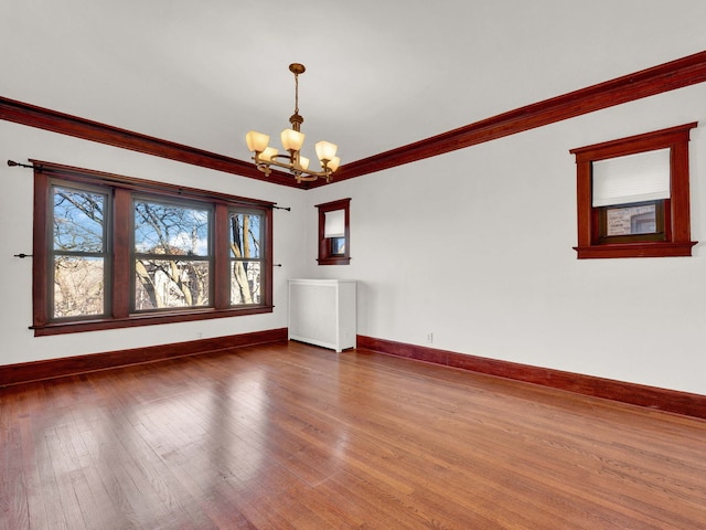 unfurnished room with hardwood / wood-style flooring, a notable chandelier, and crown molding