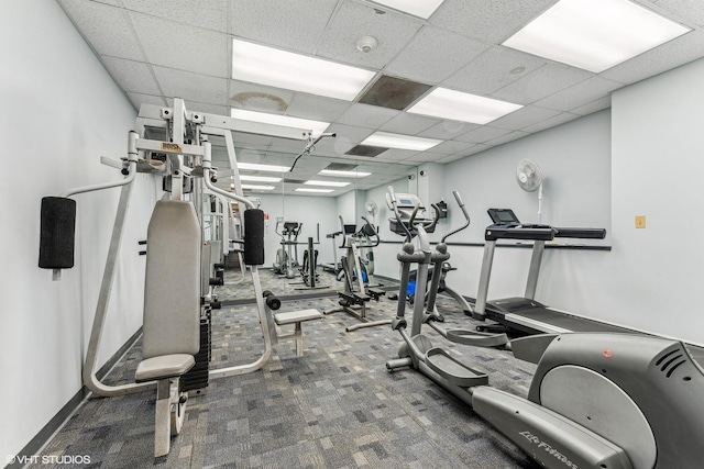 workout area featuring carpet flooring, a paneled ceiling, and baseboards