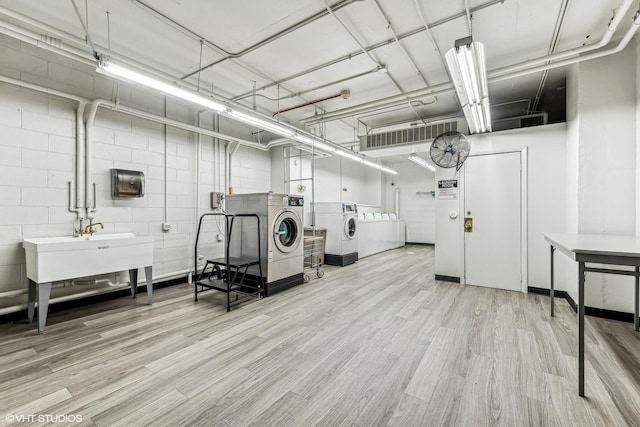 interior space featuring concrete block wall, light wood-style floors, and washer and dryer