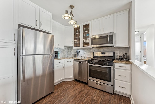 kitchen with decorative light fixtures, appliances with stainless steel finishes, glass insert cabinets, and white cabinets