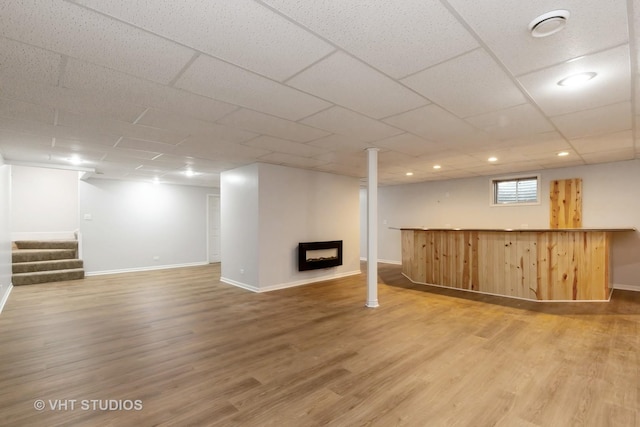 basement featuring a paneled ceiling and wood-type flooring