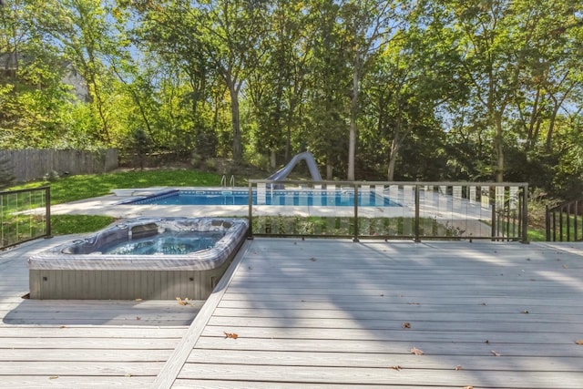 view of swimming pool featuring an outdoor hot tub, a wooden deck, and a water slide