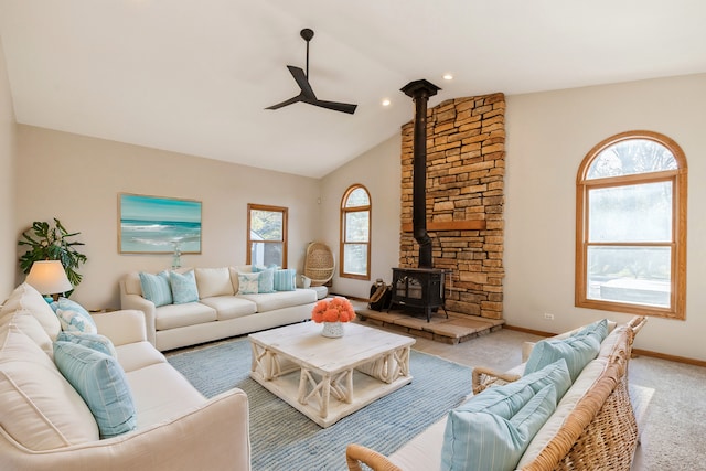 carpeted living room featuring a wood stove, ceiling fan, and vaulted ceiling