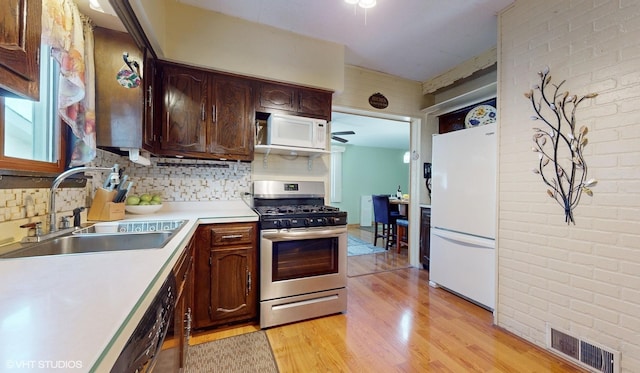 kitchen featuring dark brown cabinetry, sink, tasteful backsplash, light hardwood / wood-style flooring, and white appliances