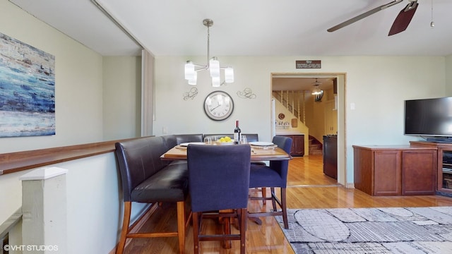 dining space featuring light hardwood / wood-style floors and ceiling fan with notable chandelier