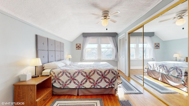 bedroom featuring ceiling fan, a textured ceiling, lofted ceiling, a closet, and hardwood / wood-style flooring