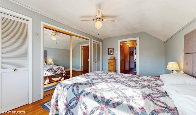 bedroom featuring two closets, ceiling fan, vaulted ceiling, and light wood-type flooring