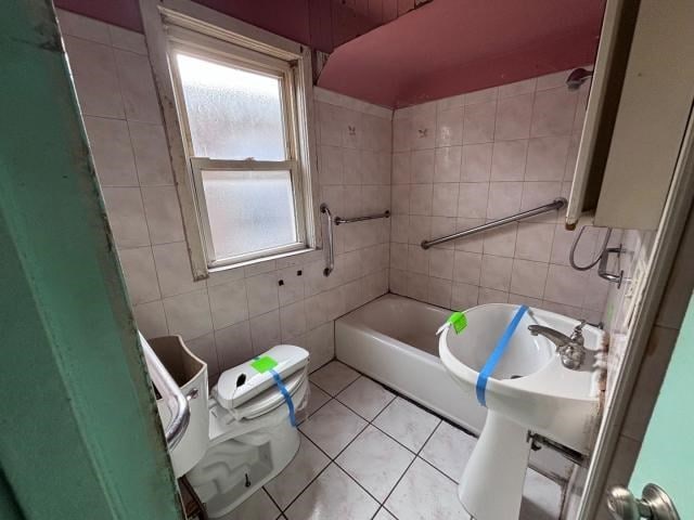 bathroom featuring tile patterned flooring, tile walls, and toilet