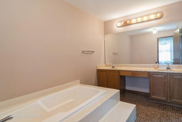 bathroom with tile patterned flooring, vanity, and tiled bath