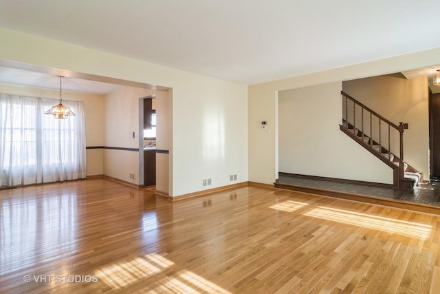 unfurnished living room with a chandelier and hardwood / wood-style flooring