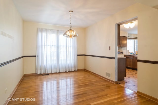 empty room featuring a chandelier and light hardwood / wood-style flooring