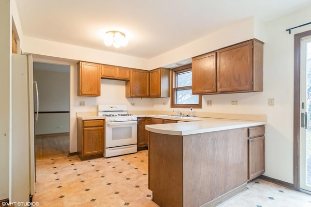 kitchen with kitchen peninsula, white appliances, and sink