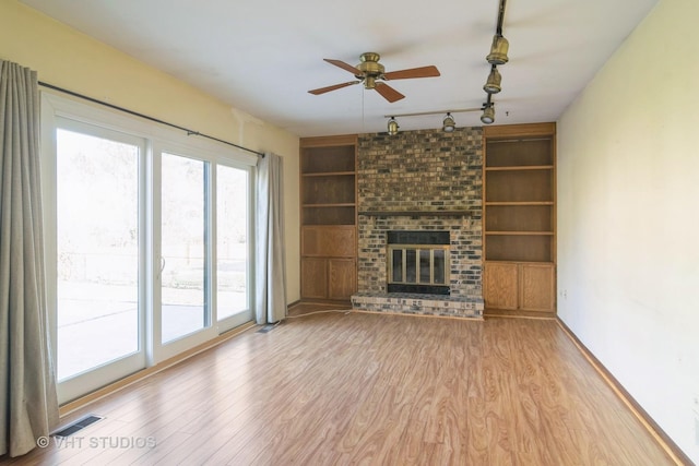 unfurnished living room featuring a fireplace, ceiling fan, built in features, and light hardwood / wood-style floors