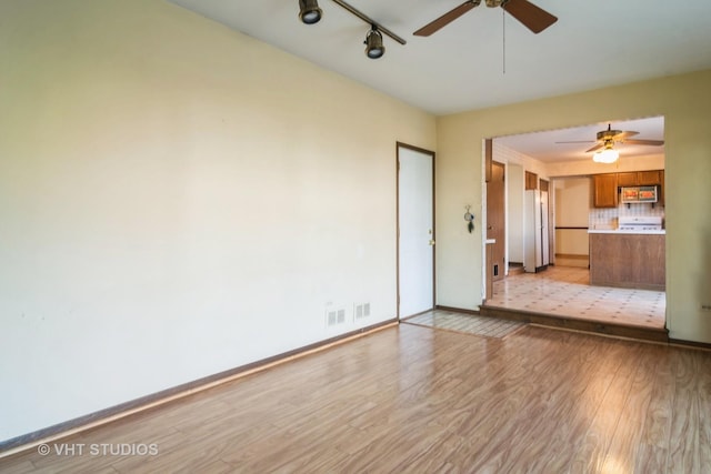 unfurnished living room featuring ceiling fan, rail lighting, and light wood-type flooring