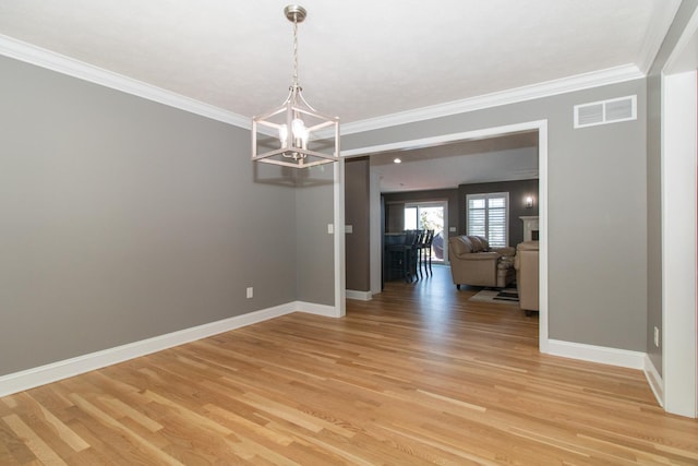 unfurnished dining area with light hardwood / wood-style floors, crown molding, and a notable chandelier