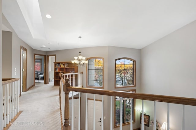 hall with light colored carpet and a notable chandelier