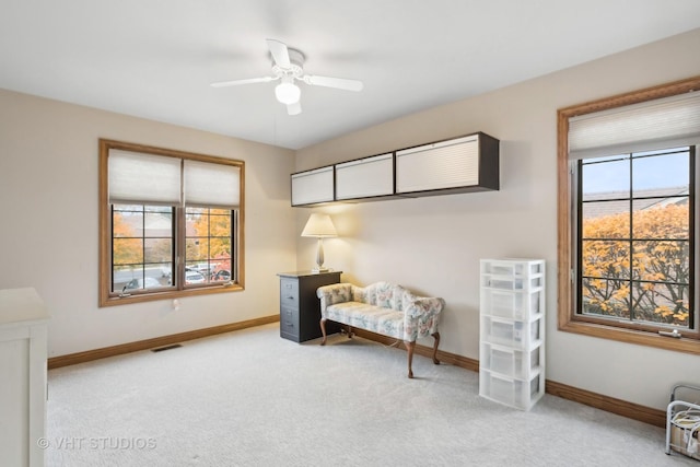 living area with light carpet and ceiling fan