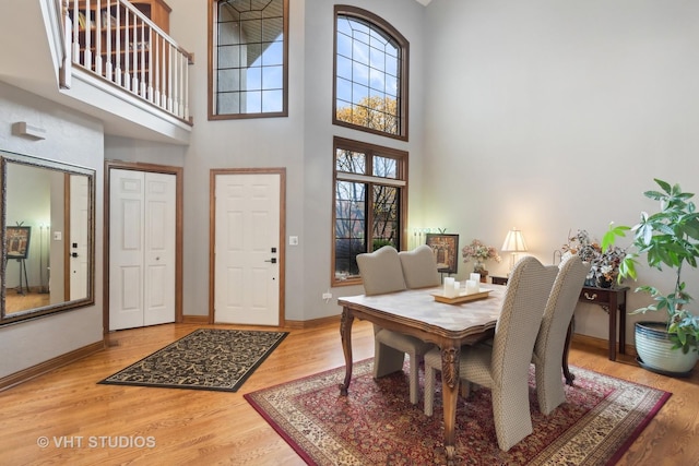 dining space featuring hardwood / wood-style floors and a towering ceiling